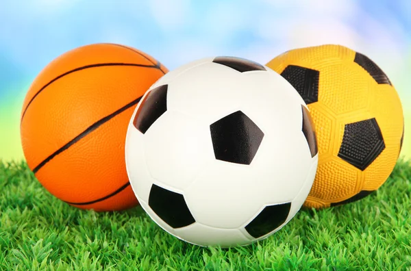 Спортивные мячи, на зеленой траве, на ярком фоне — стоковое фото