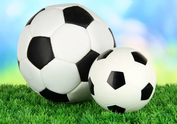 Soccer balls on green grass on bright background — Stock Photo, Image