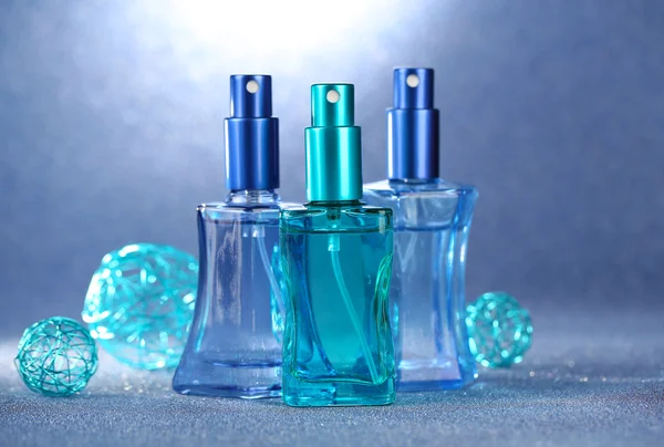 Frauen-Parfüm in schönen Flaschen auf blauem Hintergrund — Stockfoto