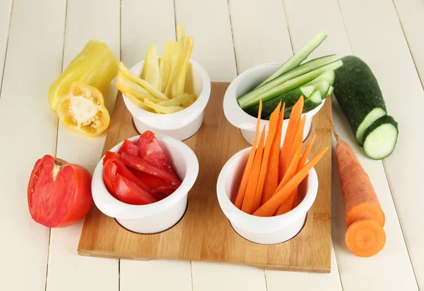 Légumes frais brillants coupés en tranches dans des bols sur une table en bois close-up — Photo