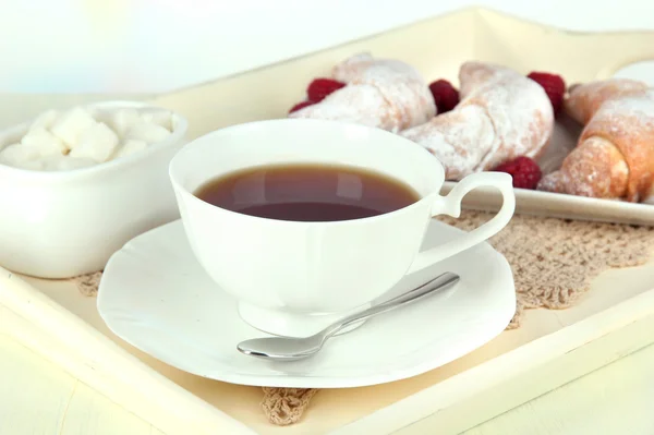 Cup of tea with cakes on wooden tray on table in room — Stock Photo, Image