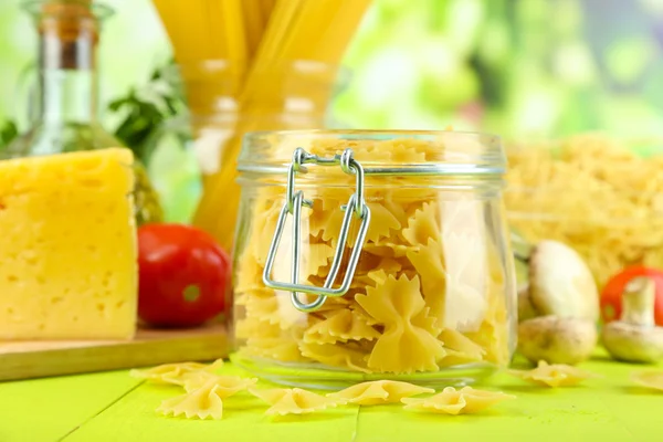 Pasta with oil, cheese and vegetables on wooden table on natural background — Stock Photo, Image