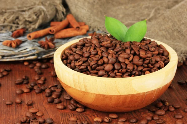 Kávová zrna v misce na dřevěné pozadí — Stock fotografie