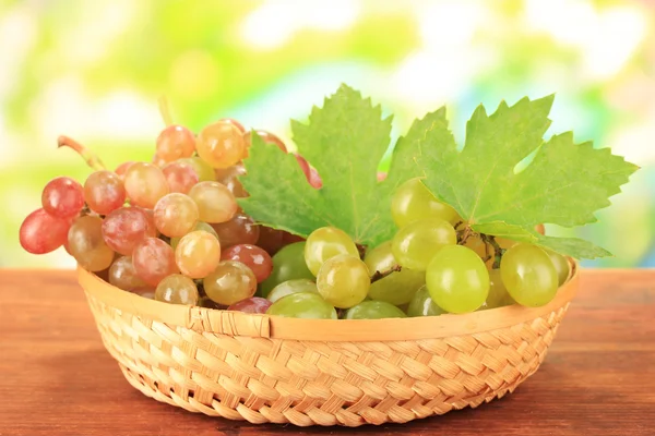 Ripe sweet grape in basket on wooden table, on nature background — Stock Photo, Image