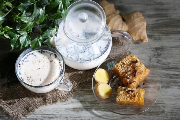 Teiera e tazza di tè con latte e spezie su sacco di tavolo in legno — Foto Stock