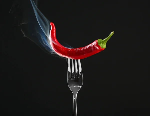 Red hot chili pepper on fork, isolated on black — Stock Photo, Image