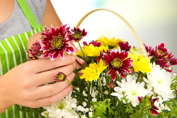 Florist makes flowers bouquet in wicker basket — Stock Photo, Image