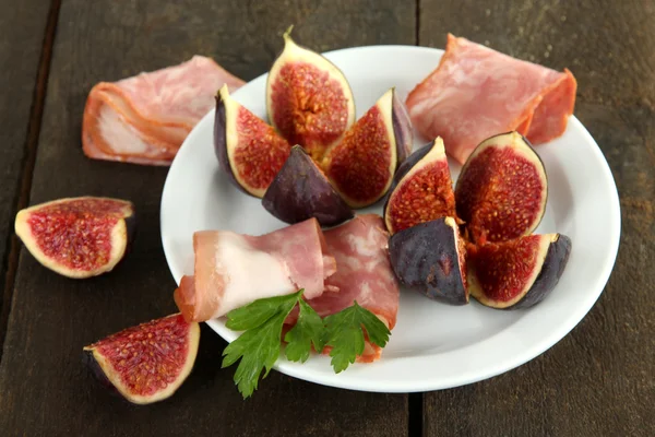 Figues savoureuses avec jambon sur table en bois gris — Photo