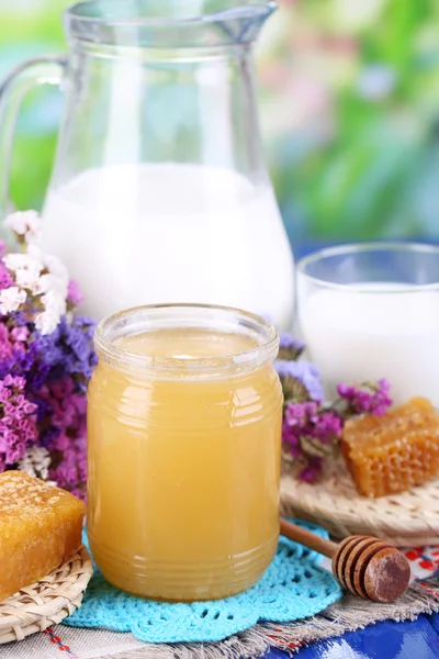 Miel et lait sur table en bois sur fond naturel — Photo