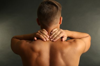 gri arka plan üzerinde boyun ağrısı olan genç adam