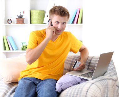 Divan laptop ve kredi kartı ile genç adam