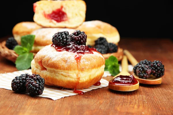 Donuts saborosos com bagas na mesa de madeira — Fotografia de Stock