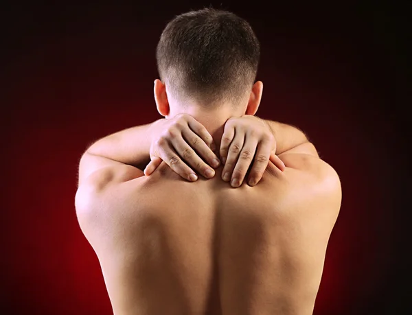 Young man with neck pain, on red background — Stock Photo, Image