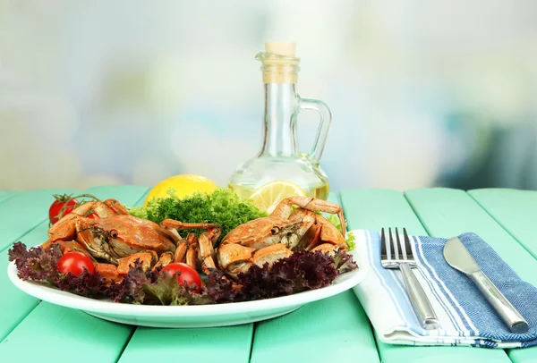 Вареные крабы на белой тарелке с листьями салата и помидорами, на деревянном столе, на ярком фоне — стоковое фото