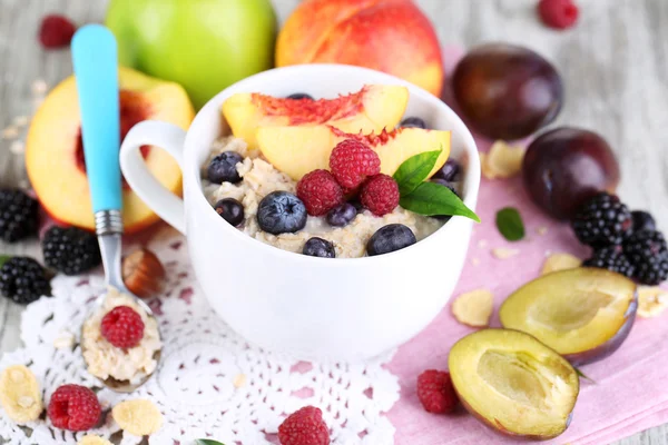 Harina de avena en taza con bayas en servilletas sobre mesa de madera — Foto de Stock