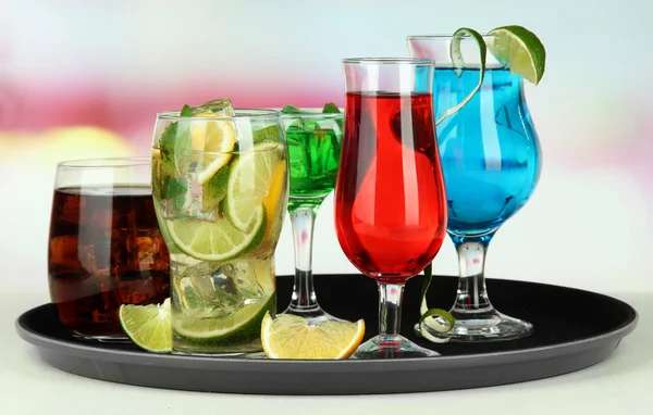 Many glasses of cocktails on tray on table, on bright background — Stock Photo, Image