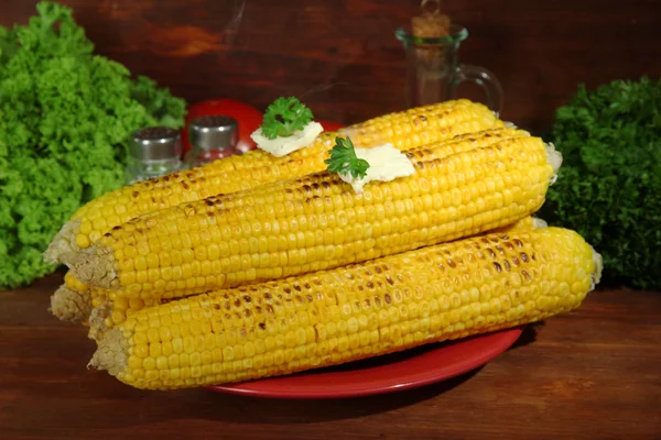 Delicioso maíz dorado a la parrilla con mantequilla en la mesa sobre fondo de madera — Foto de Stock