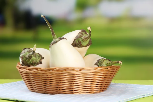 Berinjelas frescas em cesta de vime na mesa em fundo brilhante — Fotografia de Stock