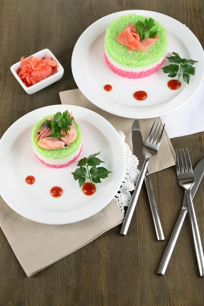 Arroz coloreado en platos en servilletas sobre mesa de madera —  Fotos de Stock