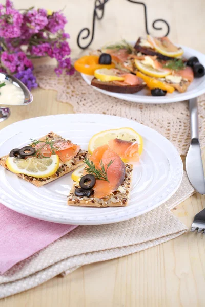 Zalm broodjes op plaat op houten tafel close-up — Stockfoto