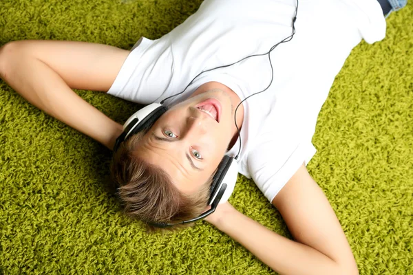 Hombre joven relajándose en la alfombra y escuchando música —  Fotos de Stock