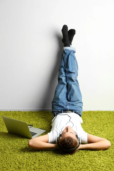 Hombre joven relajándose en la alfombra y escuchando música —  Fotos de Stock