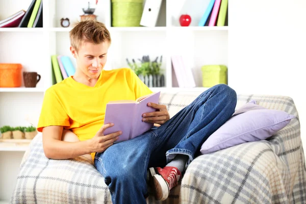 Ung man koppla av på soffan med bok — Stockfoto