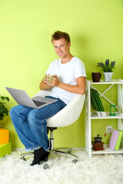 Genç erkek ev iç arka koltukta içinde laptop ile rahatlatıcı — Stok fotoğraf