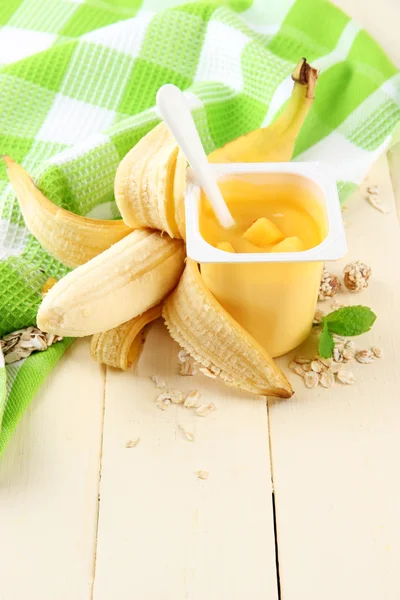 Sabroso yogur con trozos de fruta fresca, galletas y copos, sobre fondo de madera de color — Foto de Stock