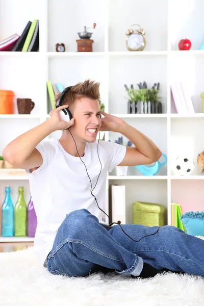 Jonge man ontspannen tapijt en luisteren naar muziek — Stockfoto