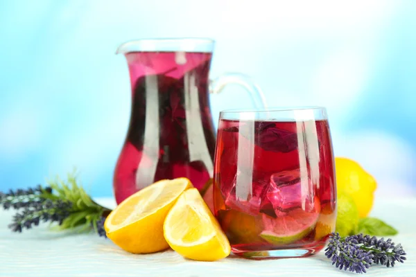 Red basil lemonade in jug and glass, on wooden table, on bright background — Stock Photo, Image