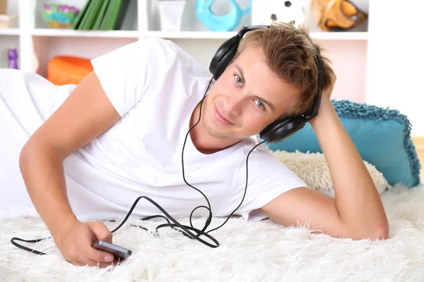 Jovem relaxando no tapete e ouvindo música — Fotografia de Stock