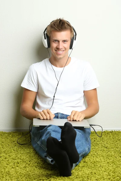 Junger Mann entspannt sich auf Teppich und hört Musik — Stockfoto