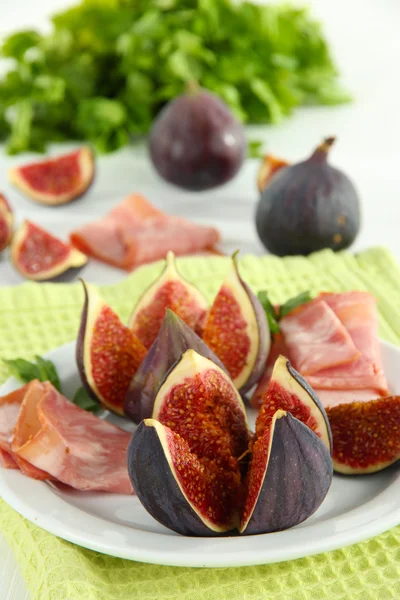 Smakelijke vijgen met ham op witte houten tafel — Stockfoto