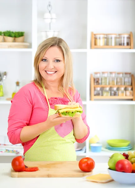 Feliz mulher sorridente na cozinha preparando sanduíche — Fotografia de Stock