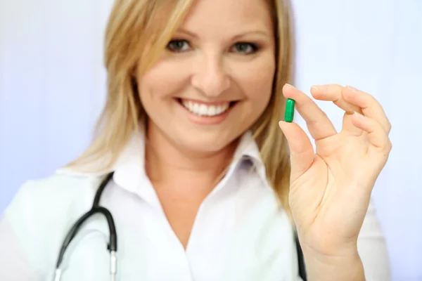 Jeune beau médecin avec stéthoscope tenant pilule multicolore, isolé sur blanc — Photo