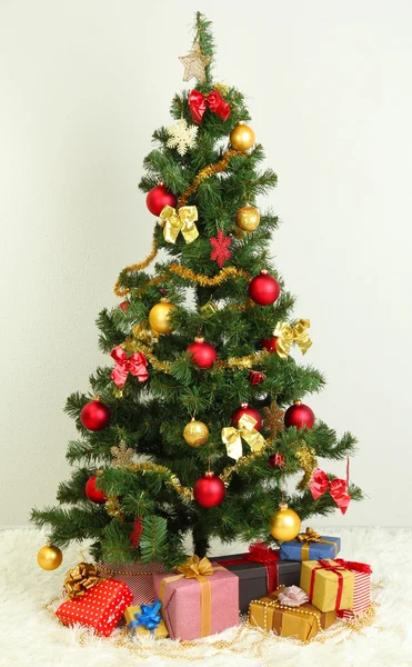 Geschmückter Weihnachtsbaum mit Geschenken auf grauem Wandhintergrund — Stockfoto