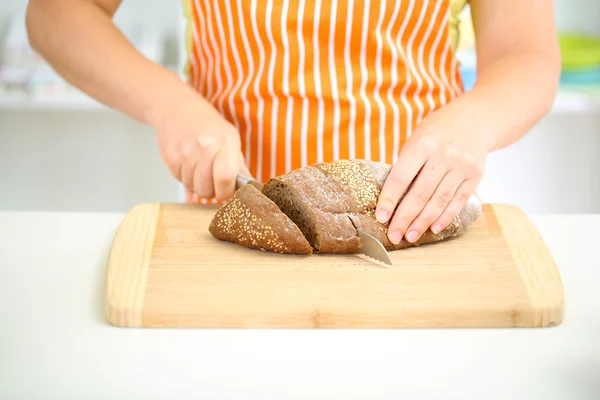 Woman slicing bread with sesame seeds on chopping board, close up — Stock Photo, Image
