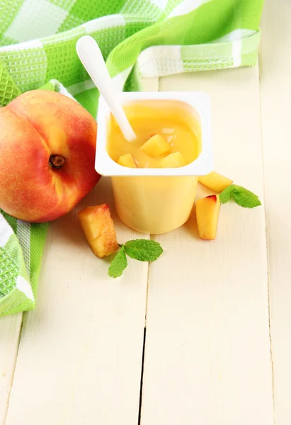 Yogurt saporito con pezzi di frutta fresca, su sfondo di legno a colori — Foto Stock