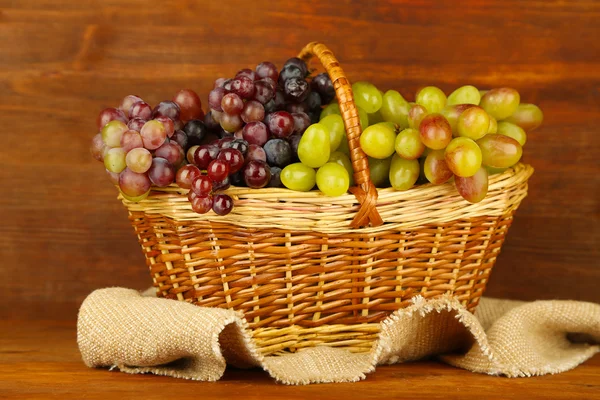 Fresh grape on wicker mat on wooden background — Stock Photo, Image