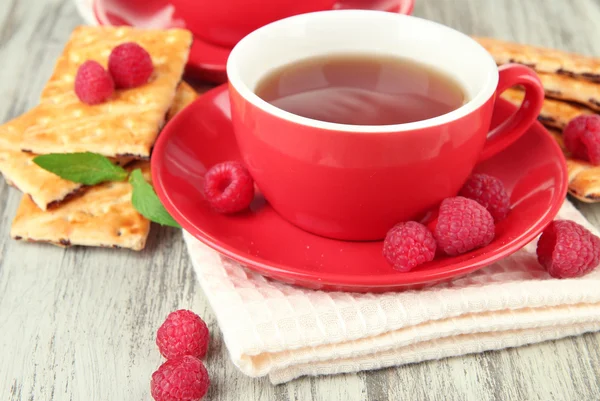 Tazas de té con galletas y frambuesas en primer plano de la mesa —  Fotos de Stock