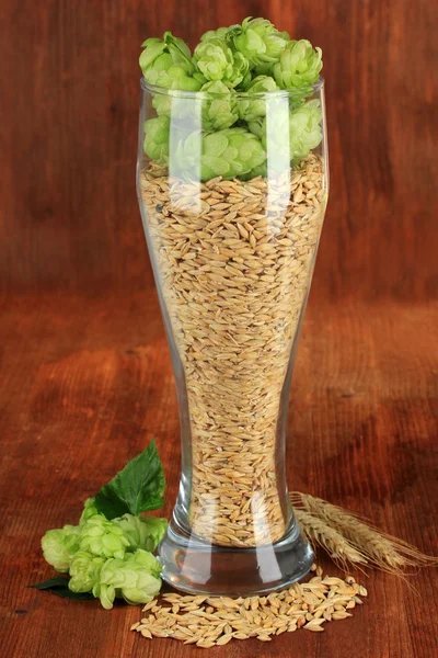 Glas frischer grüner Hopfen und Gerste, auf Holzgrund — Stockfoto