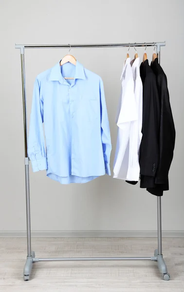Bureau vêtements masculins sur cintres, sur fond gris — Photo