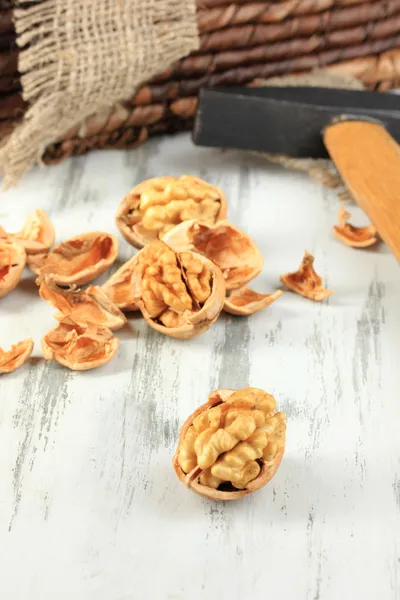 Broken walnuts with hammer on wooden table close-up Stock Photo