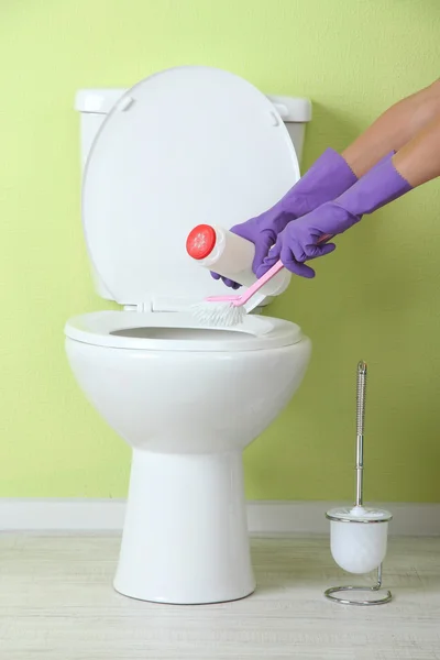 Woman hand with spray bottle cleaning a toilet bowl in a bathroom — Stock Photo, Image