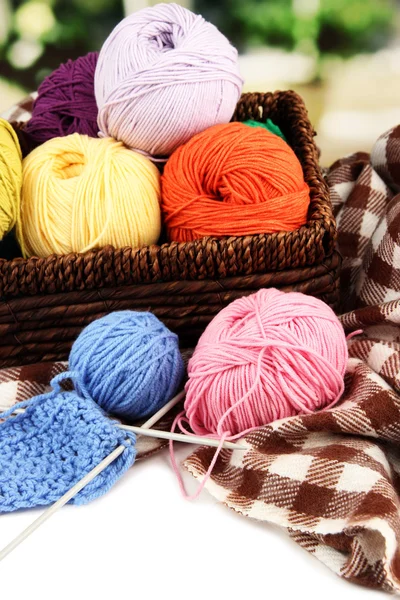 Multicolored clews in wicker basket with plaid closeup — Stock Photo, Image