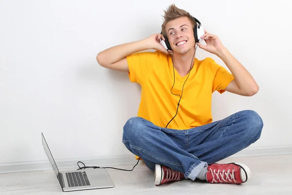 Bonito jovem ouvindo música em fundo cinza — Fotografia de Stock