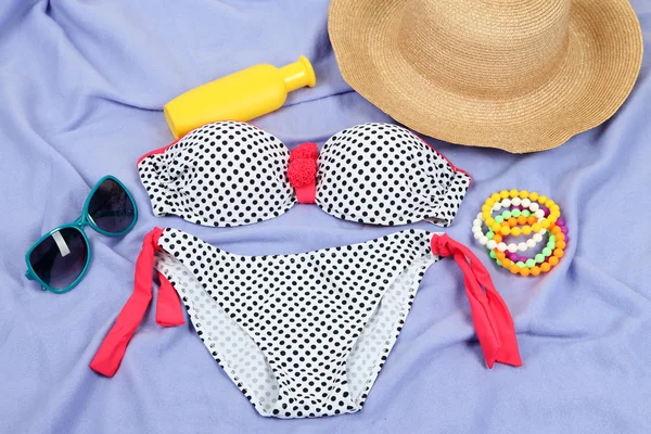 Swimsuit and beach items on purple background — Stock Photo, Image