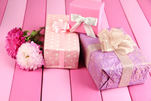 Gifts and flowers, on bright wooden background — Stock Photo, Image