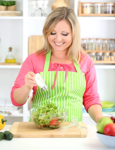 Feliz mujer sonriente en la cocina preparando ensalada de verduras —  Fotos de Stock